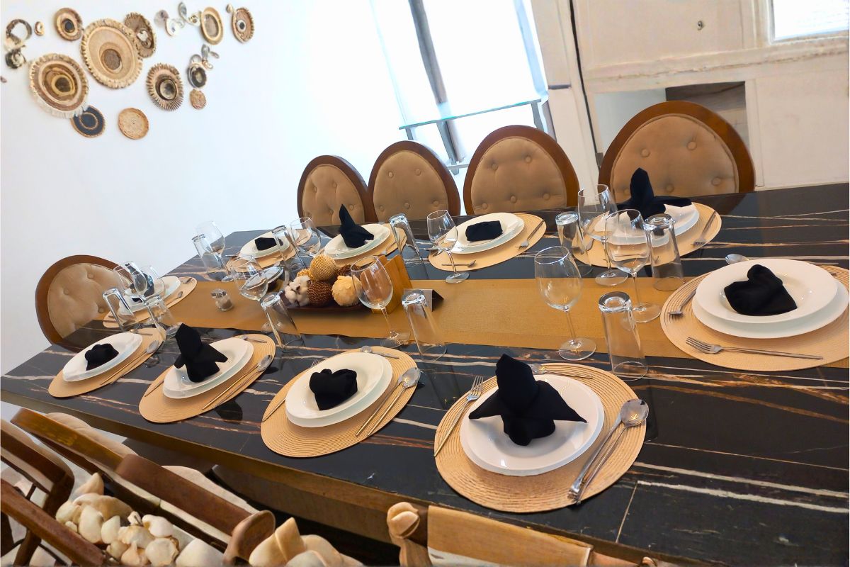 Montaje de comedor formal en Allegra Suites con vajilla blanca, servilletas negras y centro decorativo.