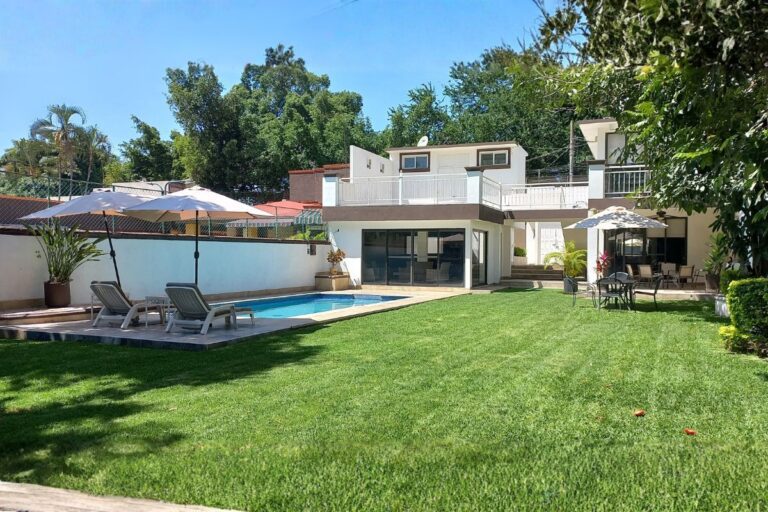 Área exterior en Eucalipto 26 con alberca, camastros, sombrillas y jardín amplio