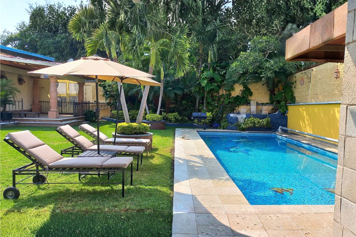 Área exterior en Las Fuentes 34-A con alberca decorada, camastros y terraza techada.