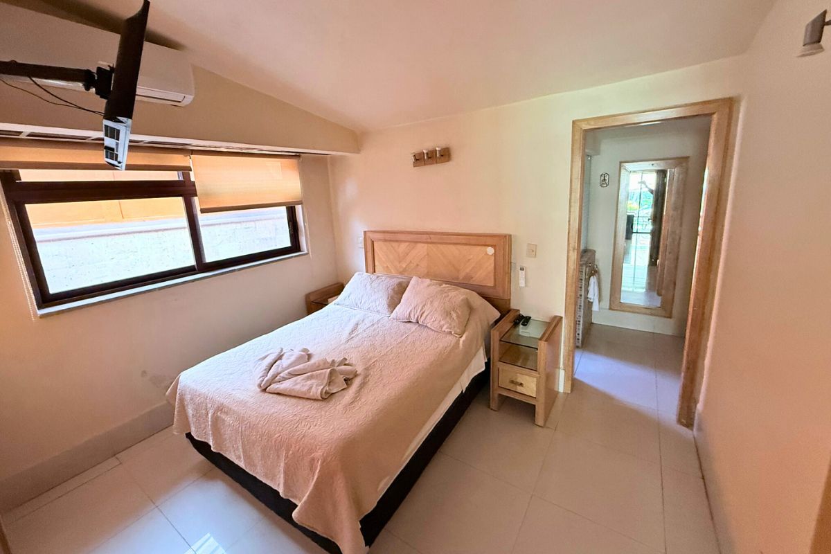 Recámara en Las Fuentes 34-A con cama queen, televisión, aire acondicionado y acceso al baño.