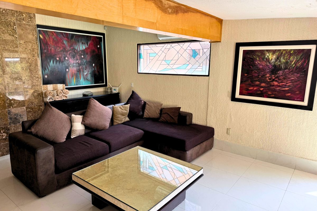 Sala en Las Fuentes 34-A con sofá seccional, mesa de centro y decoración artística.