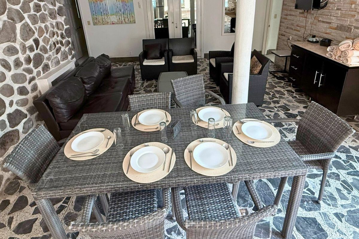 Área interior en Pedregal 20 con comedor de mimbre, sala acogedora y decoración rústica.