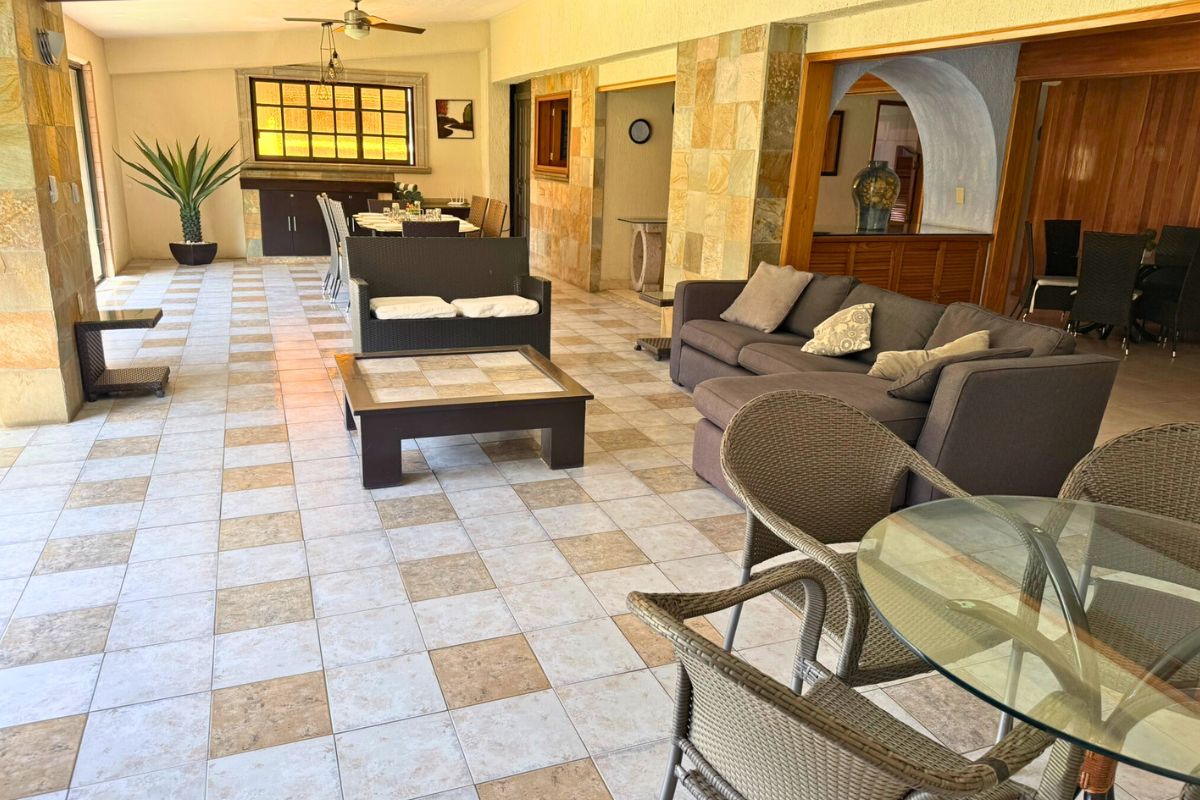 Área interior en Villa Las Fuentes con sala seccional, comedor largo y decoración en piedra.