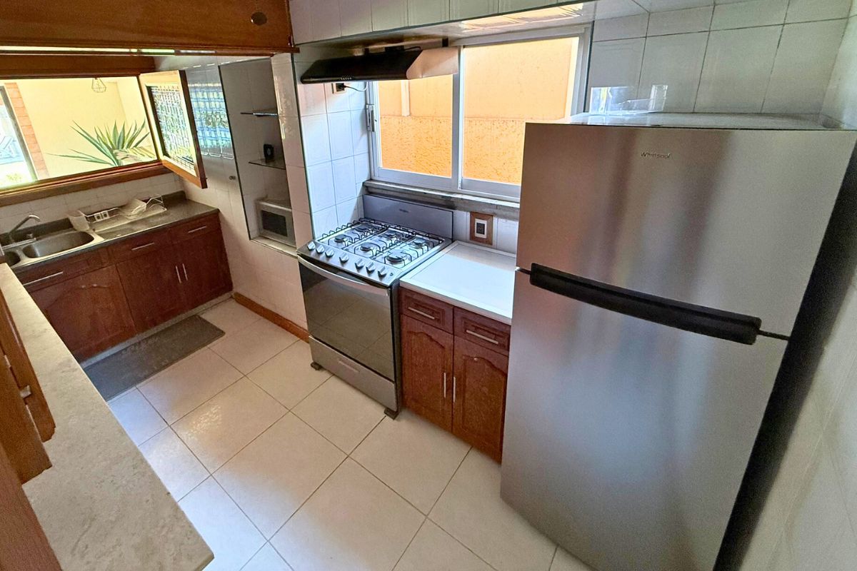 Cocina en Villa Las Fuentes con estufa, refrigerador, microondas y alacenas de madera.