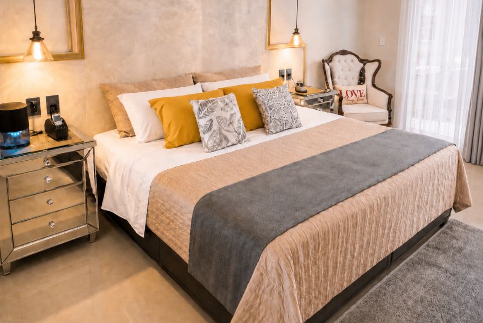 Suite Nupcial de Allegra Suites con cama king size, ropa de cama dorada y gris, sillón vintage y luces cálidas, Allegra Homes en Cuernavaca, Morelos