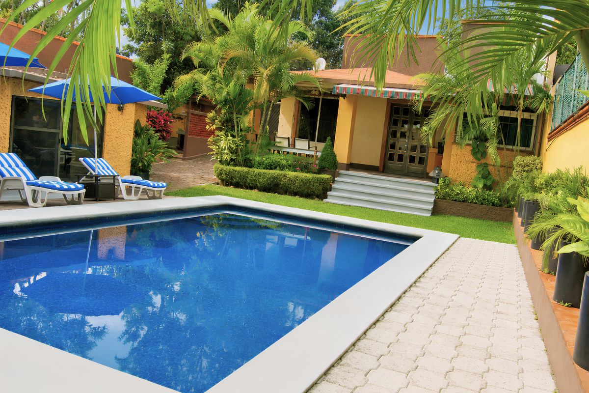 Alberca de Villas Eucalipto con terraza empedrada y acceso a la casa entre vegetación tropical, Allegra Homes en Cuernavaca, Morelos
