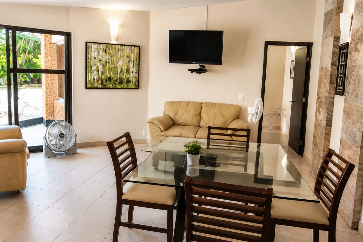 Sala comedor de Villas Eucalipto con mesa de cristal para 6 personas, sofás y acceso directo al jardín, Allegra Homes en Cuernavaca, Morelos