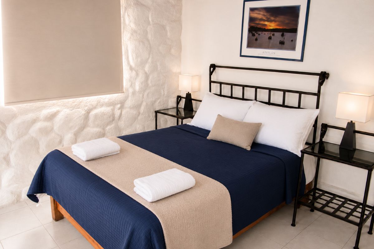 Recámara 2 de Villas Eucalipto con cama matrimonial, cabecera de herrería y pared de piedra, Allegra Homes en Cuernavaca, Morelos