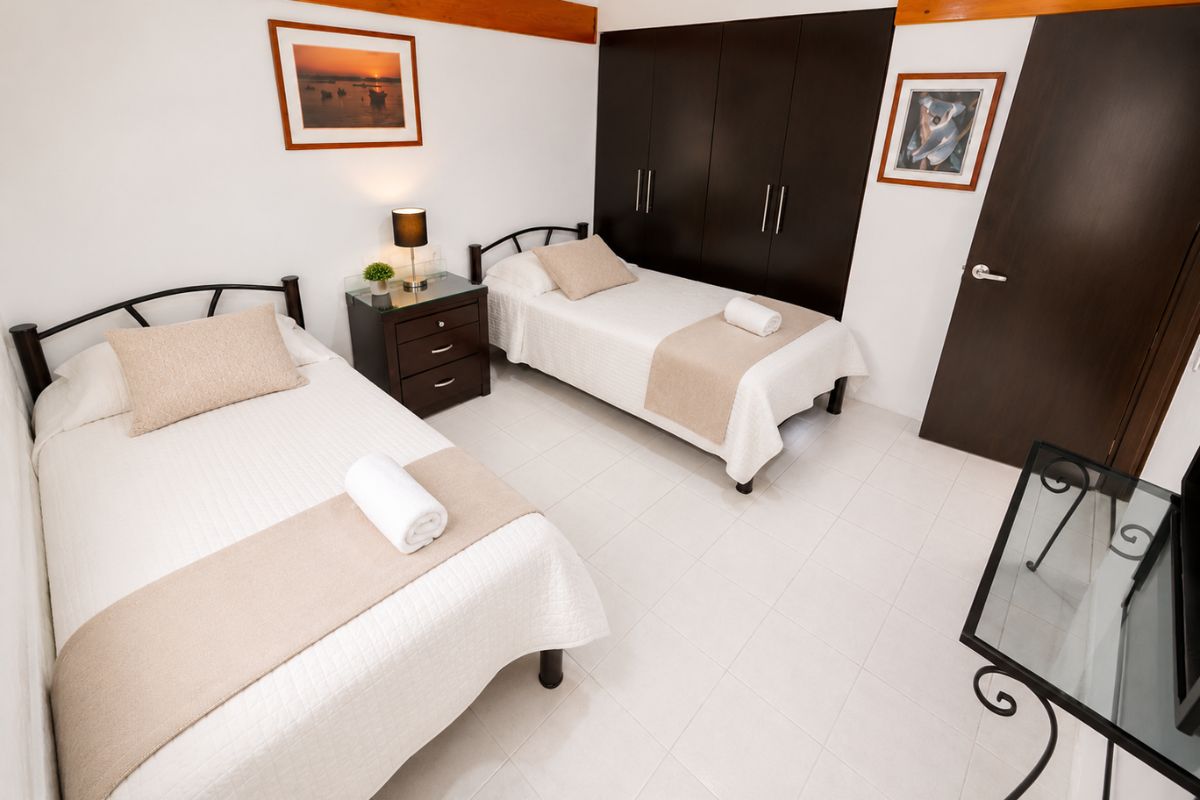 Recámara 3 de Villas Eucalipto con dos camas individuales y closet de madera oscura, Allegra Homes en Cuernavaca, Morelos