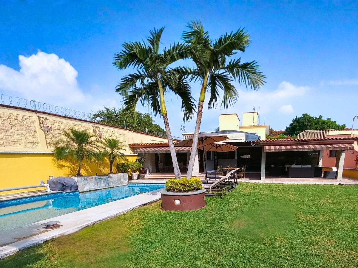 Alberca rectangular con césped y palmeras altas, casa Las Fuentes 34-A en Cuernavaca