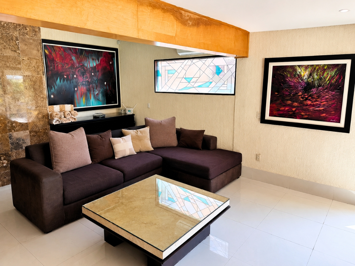 Sala de estar con sofá seccional morado y cuadros abstractos, casa Las Fuentes 34-A en Cuernavaca