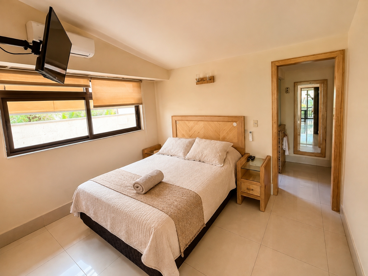 Recámara matrimonial con TV en la pared y vista al baño integrado, casa Las Fuentes 34-A en Cuernavaca