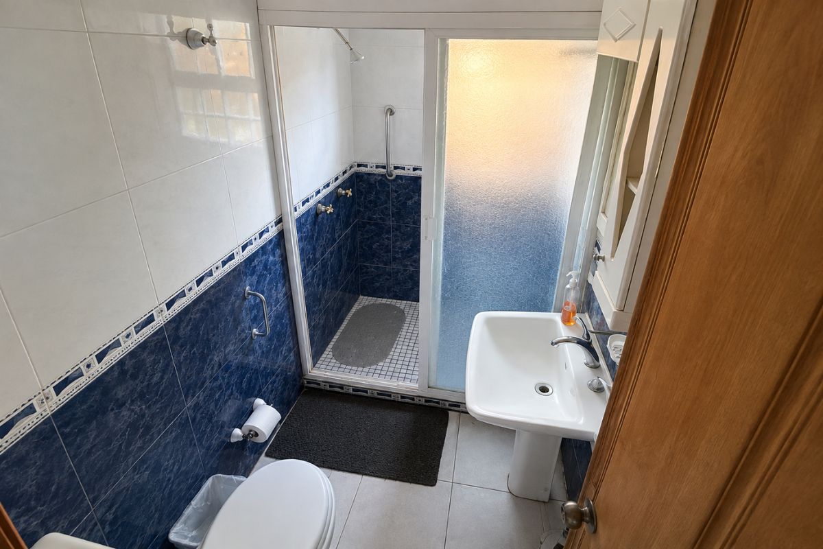 Baño con azulejo azul y regadera en Villa Las Fuentes, Cuernavaca