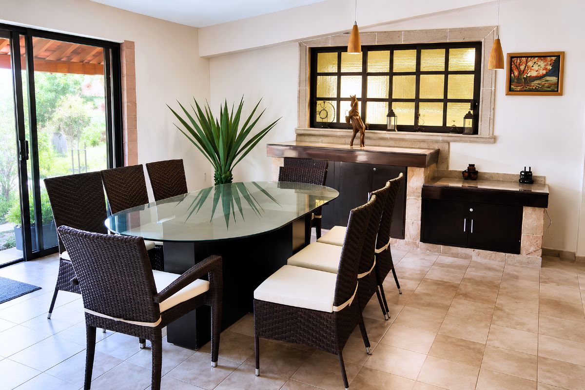 Comedor con mesa de vidrio y sillas de mimbre en Villa Las Fuentes, Cuernavaca