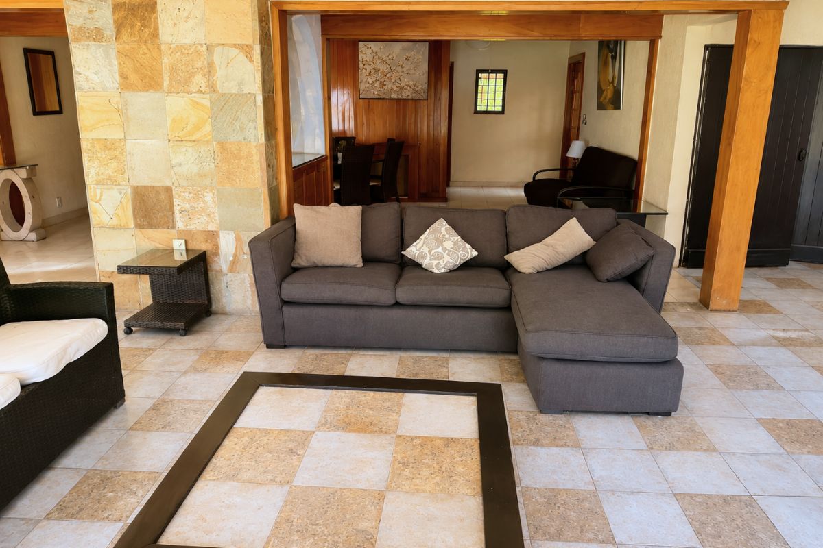 Sala con sofá seccional gris y piso ajedrezado en Villa Las Fuentes, casa de fin de semana en Cuernavaca